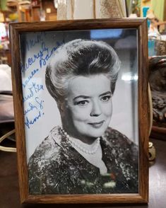 an old photo of a woman with short hair in a wooden frame on a table