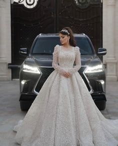 a woman standing in front of a car wearing a dress with long sleeves and pearls on it