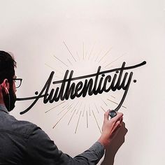 a man writing the word authenticity on a wall