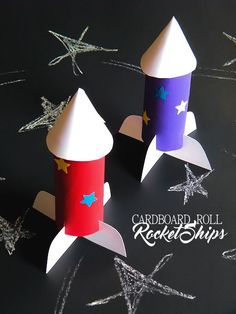 two paper rockets sitting on top of a black table next to star shaped confetti cones