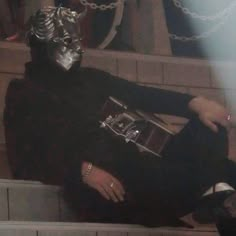 a man in a costume sitting on some steps with chains around his neck and legs