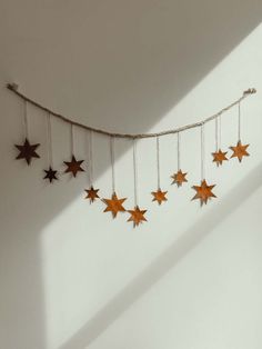 stars are hanging from the ceiling in a room with white walls and shadows on the wall