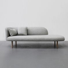 a gray couch with two pillows on it and a white wall in the back ground