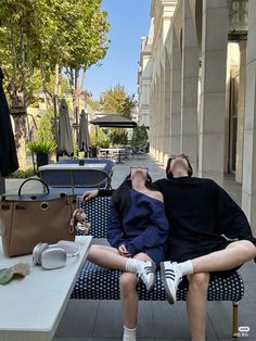 a man and woman laying on a bench next to each other in front of a building