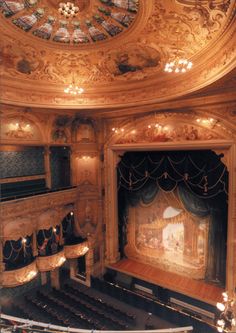 an ornately decorated auditorium with chandeliers and stained glass window above the stage