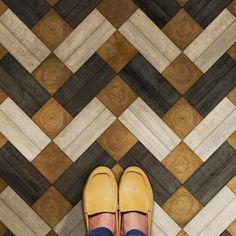 a pair of yellow shoes sitting on top of a wooden floor next to a person's feet