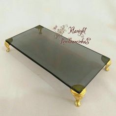 a black glass tray with gold legs on a white background