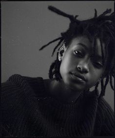 a black and white photo of a woman with dreadlocks looking at the camera