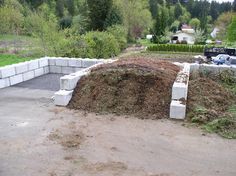 a pile of dirt sitting in the middle of a parking lot next to a forest