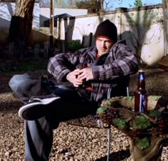 a man sitting on a bench with a beer in his hand