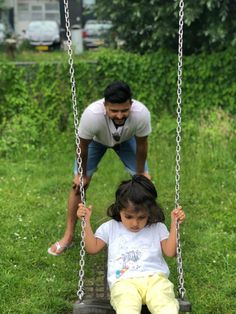 a father and daughter playing on a tire swing