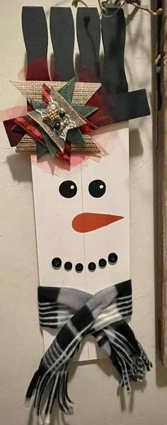 a snowman made out of wood sticks and ribbon on the side of a wall