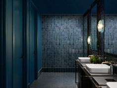 a bathroom with two sinks, mirrors and blue tiles on the wall above them is an open door that leads to another room