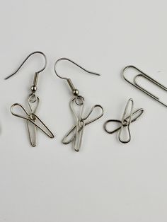 three pairs of scissors hanging from hooks on a white surface with clippings attached to them