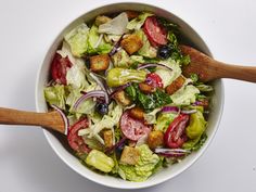 a salad in a white bowl with wooden spoons on the side, ready to be eaten