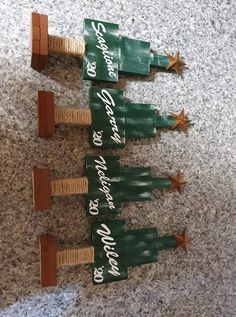 three wooden christmas trees on the ground with words written on them and stars attached to them