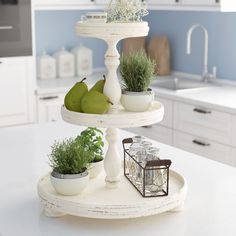 three tiered trays with plants and fruit on them in a kitchen setting,