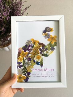 a person holding up a frame with flowers in it