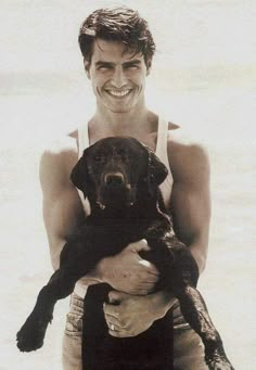 a man holding a dog in his arms on the beach