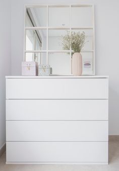 a white dresser with a mirror and vase on top