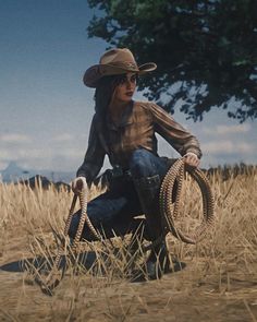 a woman kneeling in the middle of a field with a rope wrapped around her legs