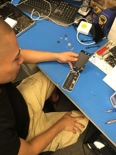 a man sitting at a desk working on an electronic device with multiple wires and tools