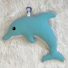 a blue stuffed dolphin laying on top of a white blanket next to a bottle opener