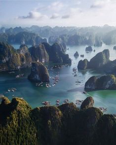 an aerial view of many boats in the water surrounded by mountains and rocks with green vegetation