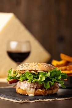 a close up of a sandwich on a plate with french fries and a glass of wine in the background