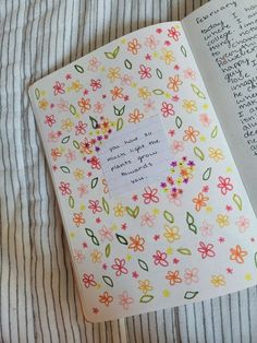 an open book with flowers on it and a note pinned to the page next to it