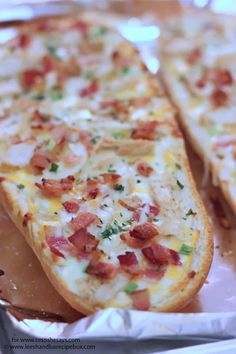 two slices of bread with bacon and cheese on them sitting in a tin foil container