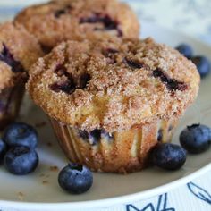 two blueberry muffins on a plate with fresh blueberries