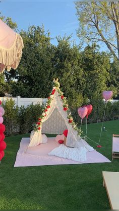 a teepee tent is set up on the lawn for a wedding party with pink and red balloons