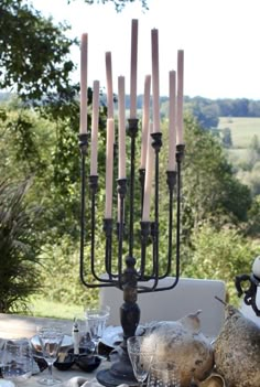 an outdoor table with candles and dishes on it