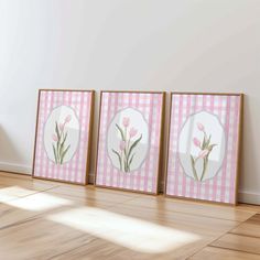 three framed pictures on the wall with pink flowers and gingham checkerboard