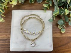 "This GORGEOUS 14k DOG MOM 🐶 Gold filled beaded bracelets are a perfect set for any dog lover! You can order the single Dog Mom bracelet, or save and add to your stack with a 4mm Gold bracelet that has a Paw Charm. ★ Save $5 when you order the entire stack 🐾 These bracelets and charm are made with 14K Gold and premium stretch cord. The Dog Mom bracelet is 3mm and the paw bracelet is 4mm.  For best fit, measure your wrist with a measuring tape or string (see attached picture for directions). Add 1/2\" to that measurement for a snug fit, 3/4\"  for a comfort fit, or 1\" for a loose fit. ★ If you don't see your size, please send me a message.  ★Care Instructions: These gold bracelets will not tarnish or fade if you care for them properly. Just like any gold jewelry, avoid lotions, perfumes Gold Bracelets Stacked, Mom Bracelet, Gold Beaded Bracelet, Moms Bracelet, Gold Armband, Ball Bracelet, Gold Bead Bracelets, Gold Charm Bracelet, Gold Bracelets