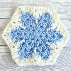 a blue and white crocheted square on a wooden surface