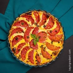 a tomato and cheese quiche on a blue cloth