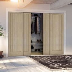 an empty room with two doors open and shoes hanging on the closet door, in front of a potted plant