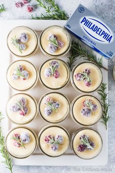 small desserts are arranged on a white tray with rosemary sprigs and powdered sugar