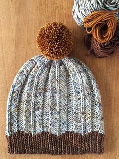 two balls of yarn sitting next to each other on a wooden surface with one ball of yarn in the foreground