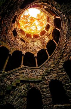 the inside of an old stone building with a light shining in it's center