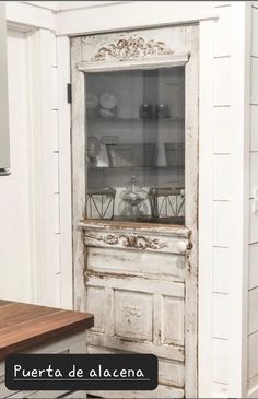 an old door is opened to reveal a kitchen with white walls and wood flooring