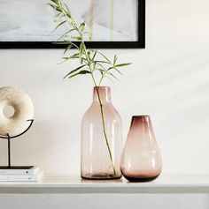 two pink vases sitting on top of a white table next to a book shelf