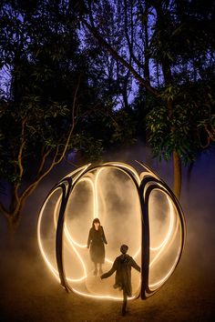 two people standing in front of a circular light sculpture