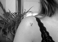 the back of a woman's shoulder with a small triangle tattoo on her upper arm