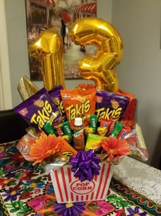 an arrangement of candy and foil balloons on a table with the number twenty five in the background