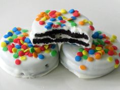 three white cake donuts covered in sprinkles with one slice cut out