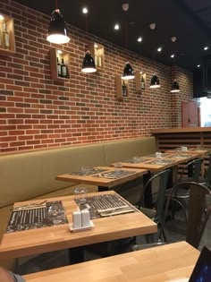 an empty restaurant with tables and chairs in front of a brick wall that has lights hanging from the ceiling