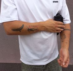 a man with a tattoo on his arm holding a cell phone in his other hand